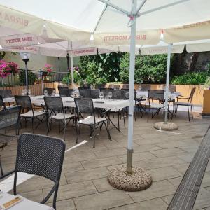 a group of tables and chairs with white umbrellas at Hotel Giardino del Sole in Savona