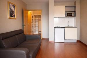 a living room with a couch and a kitchen at Les Balcons du Sancy - Résidence de Tourisme in Picherande