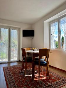 a dining room with a table and chairs and windows at Casa Verde Valsassina 2 in Primaluna