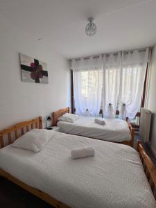two beds in a bedroom with a window at Cosy 4 pers in Chalon-sur-Saône