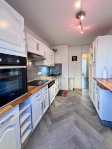 a kitchen with white cabinets and wooden counter tops at Cosy 4 pers in Chalon-sur-Saône +13 photos