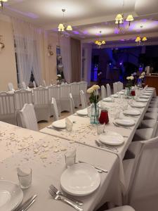 a long table with white plates and silverware on it at Zajazd Jerzmanowa in Jakubów
