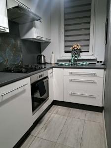 a kitchen with white cabinets and a vase of flowers at JULIA Apartament- Oświęcim in Oświęcim
