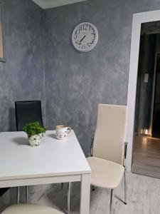 a white table and chairs with a clock on the wall at JULIA Apartament- Oświęcim in Oświęcim +1 photo