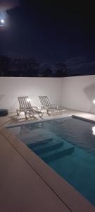 two lounge chairs and a swimming pool at night at Brava in Vila Franca do Campo