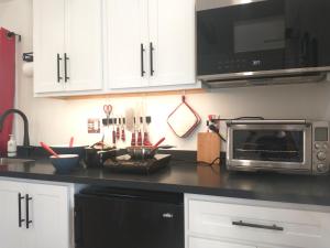 a kitchen counter with a microwave and a stove top oven at Garden Guest Cottage in Harrisonburg +3 photos
