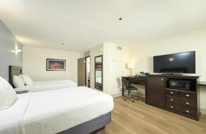 a hotel room with a bed and a desk with a television at Canad Inns Destination Centre Fort Garry in Winnipeg