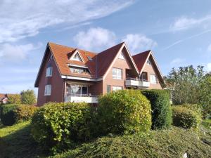 a large house with bushes in front of it at Paula - gemütliche Maisonette auf Fehmarn in Fehmarn