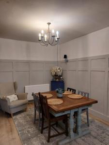 a dining room with a table and chairs and a chandelier at Pondside Cottage in Carmarthen