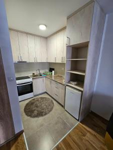 an empty kitchen with white cabinets and a rug at Garden Doboj in Doboj