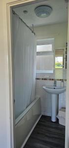 a bathroom with a shower curtain and a sink at Seafields Chalet in Walcott +14 photos