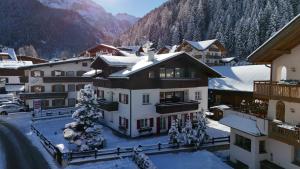 a building with snow on the ground in front of a mountain at Eden Dolomites in Selva di Val Gardena