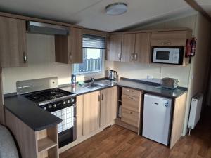 a small kitchen with a stove and a sink at Glasyln 37 in Porthmadog