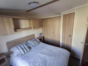 a bedroom with a bed and wooden cabinets at Glasyln 37 in Porthmadog