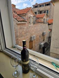 a bottle of wine sitting on a window sill with two wine glasses at Apartman Stari grad, Budva in Budva