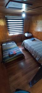 a bedroom with two beds in a room with a window at Refugio PARQUE NACIONAL ALERCE ANDINO in Puerto Montt