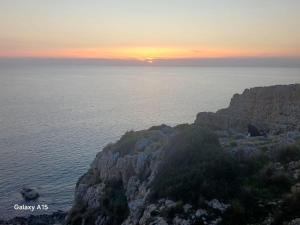 a sunset over the ocean on a rocky cliff at La Cilinella del Salento in Copertino