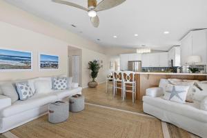 a living room with two white couches and a kitchen at Sip of Sun in New Smyrna Beach