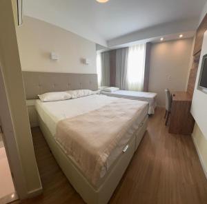 a hotel room with two beds and a window at Hotel Treviso suítes in Linhares