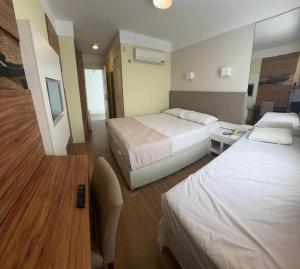 a hotel room with two beds and a television at Hotel Treviso suítes in Linhares