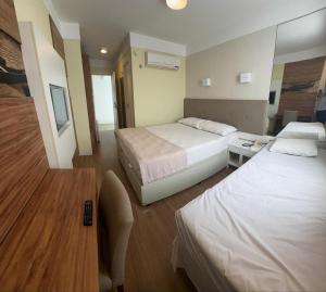 a hotel room with two beds and a television at Hotel Treviso suítes in Linhares