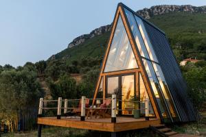 a glass house on a wooden platform with mountains in the background at Funky Cabins Villas and Chalets - Gaia Park in Tirana