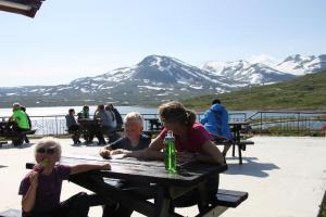 a woman and two children sitting at a picnic table at Tyinholmen hytter in Eidsbugarden
