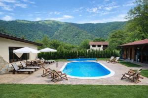 a swimming pool with chairs and a patio with mountains in the background at Къща за гости Гергана in Ribarica