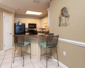 a kitchen with two chairs and a counter with a refrigerator at Phoenix VI 61509 in Orange Beach