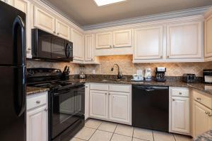 a kitchen with white cabinets and black appliances at Phoenix VI 61509 in Orange Beach