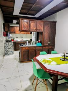 a kitchen with wooden cabinets and a table with green chairs at Casa com Piscina Grande em Salinas in Salinópolis