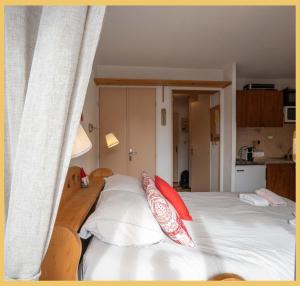 a bed with white sheets and red pillows on it at Chez Candide I Studio I Montriond in Montriond