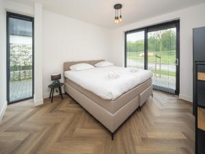 a bedroom with a white bed and wooden floors at Harderwold Villa - 551 in Zeewolde
