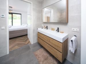 a bathroom with a white sink and a bed at Harderwold Villa - 551 in Zeewolde