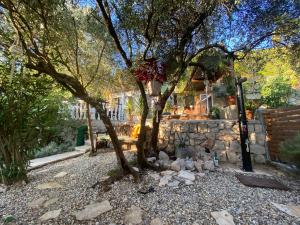 a house with two trees and a stone wall at Apartment MiriMore in Hodilje