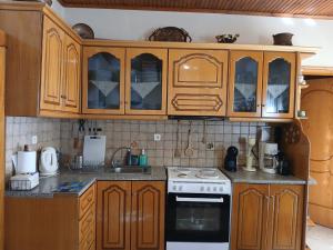 a kitchen with wooden cabinets and a stove top oven at Family PlayHouse - Villa Mitsi Sarande in Sarandë