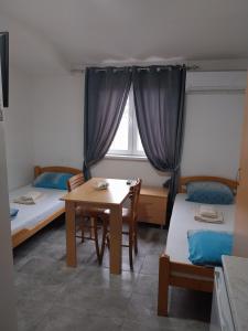 a room with two beds and a table and a window at LIBERO APARTMANI in Surčin +1 photo