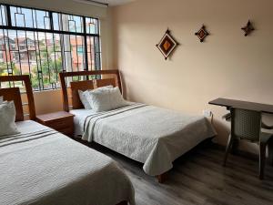 a room with two beds and a desk and a window at Casa Bachué Hotel Boutique in Chía
