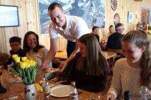 a man serving a group of people at a restaurant at Tyinholmen hytter in Eidsbugarden +4 photos