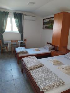 a room with two beds and a table and chairs at LIBERO APARTMANI in Surčin