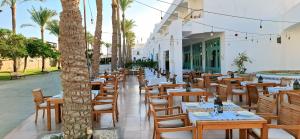 a restaurant with wooden tables and chairs and palm trees at Sharm Hills Azure Paradise in Sharm El Sheikh