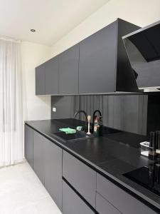 a kitchen with a black counter and a sink at La Priva House in Charleroi