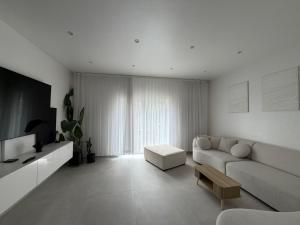 a white living room with a couch and a table at La Priva House in Charleroi