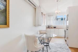 a white kitchen with a glass table and white chairs at Hobart Retreats - Sanctuary and Haven in Hobart