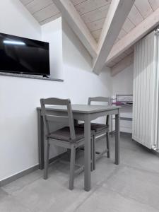 a table with two chairs and a tv on a wall at Azalea Appartamenti in Cannobio