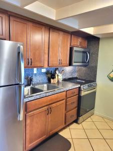 a kitchen with wooden cabinets and a stainless steel refrigerator at Molokai Kepuhi Beach Gem in Kepuhi