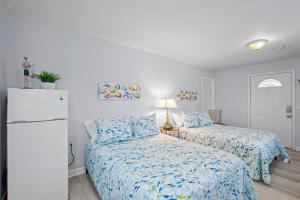 a bedroom with two beds and a refrigerator at Vitamin Sea Suites 3 in Carolina Beach