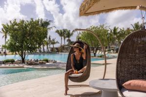 a woman sitting in a chair by a pool at The St. Regis Cap Cana Resort in Punta Cana +153 photos
