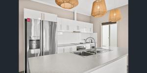 a kitchen with a stainless steel refrigerator and white cabinets at Aldinga Beach Reef Escape in Aldinga Beach