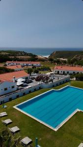 an overhead view of a large swimming pool with the ocean at Monte Carvalhal da Rocha in Zambujeira do Mar
